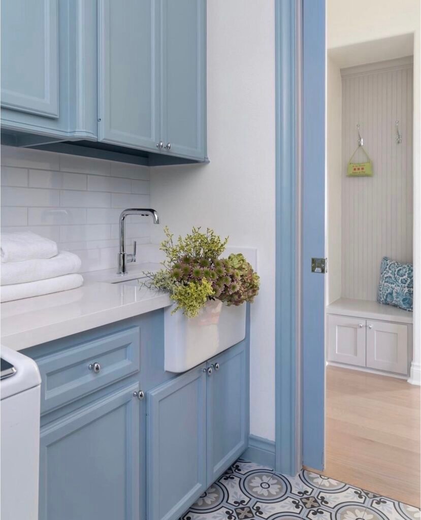 A bright bathroom featuring a blue accent wall, wood vanity, and neatly styled towels.